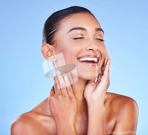 Image of Skincare, beauty and face of happy woman in studio with blue background and dermatology or cosmetics for healthy glow. Indian, model and happiness with hands on natural skin, facial or self care