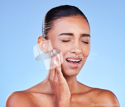 Image of Dental hygiene, pain and woman with toothache, cavity and plaque on a blue studio background. Person, girl and model with oral care, touching her sore cheek and medical issue with emergency or crisis