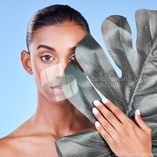 Image of Natural beauty, woman and face, monstera leaf and glow with wellness and eco friendly dermatology on blue background. Sustainable skincare, green with collagen and cosmetics in portrait in studio