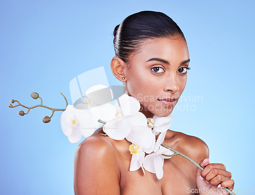 Image of Natural beauty, woman and face, flower and glow with wellness and eco friendly dermatology isolated on blue background. Sustainable skincare, orchid with collagen and cosmetics in portrait in studio