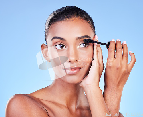 Image of Woman, mascara and makeup, beauty and brush with transformation and cosmetic product on blue background. Eyelash extension, cosmetology and volume with Indian model, wellness and change in a studio