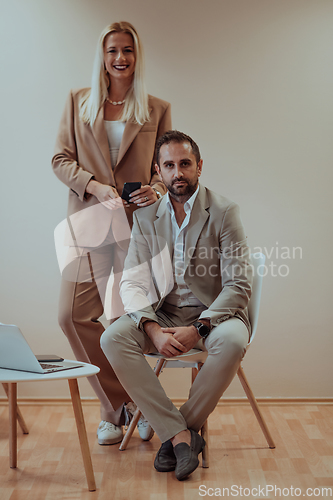 Image of A business couple posing for a photograph together against a beige backdrop, capturing their professional partnership and creating a timeless image of unity and success.