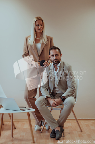 Image of A business couple posing for a photograph together against a beige backdrop, capturing their professional partnership and creating a timeless image of unity and success.