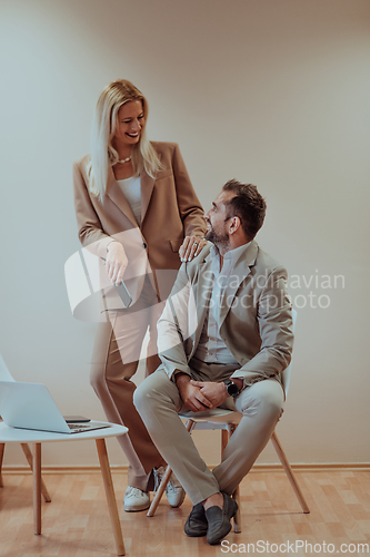 Image of A business couple posing for a photograph together against a beige backdrop, capturing their professional partnership and creating a timeless image of unity and success.