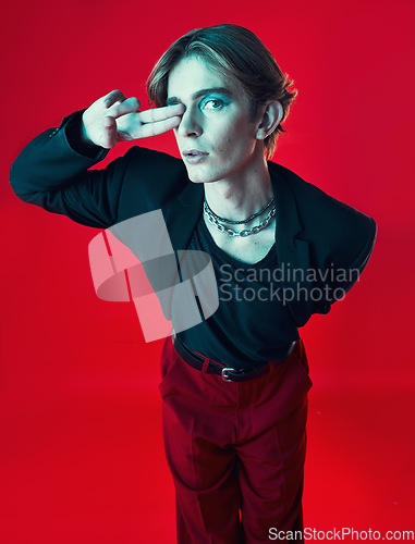 Image of Gay, man and portrait with fashion, beauty and peace sign on studio red background with unique aesthetic with makeup. Lgbt, style and model with hand in photography, grunge or retro clothing