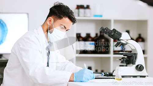 Image of Scientist and research or medical engineer doing experiments to create a cure in a lab while wearing a mask. Healthcare professional working with science equipment and writing notes in a laboratory