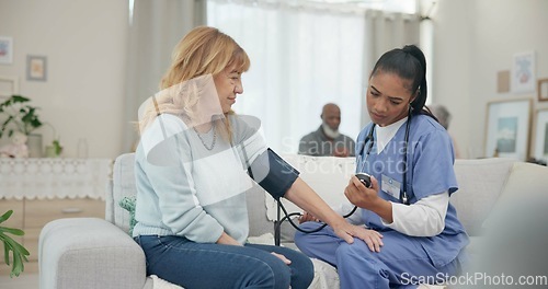 Image of Nurse, appointment and blood pressure with senior woman at nursing home for wellness. Caregiver, service and elderly female for consultation in living room for diabetes with communication for health.