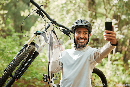 Image of Man, bicycle and forest for selfie, smile and web for wellness, training and blog on adventure. Influencer guy, cycling and mountain bike for profile picture, memory or live streaming on social media