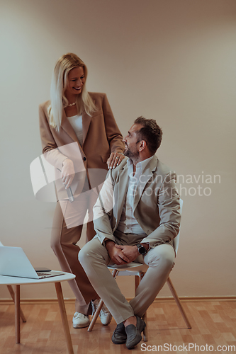 Image of A business couple posing for a photograph together against a beige backdrop, capturing their professional partnership and creating a timeless image of unity and success.