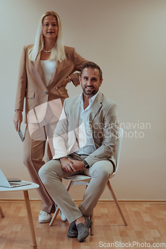 Image of A business couple posing for a photograph together against a beige backdrop, capturing their professional partnership and creating a timeless image of unity and success.