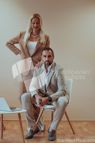 Image of A business couple posing for a photograph together against a beige backdrop, capturing their professional partnership and creating a timeless image of unity and success.