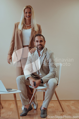 Image of A business couple posing for a photograph together against a beige backdrop, capturing their professional partnership and creating a timeless image of unity and success.