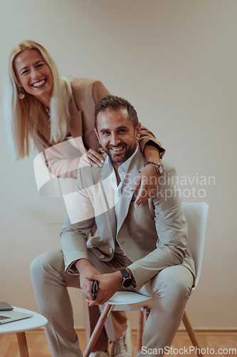 Image of A business couple posing for a photograph together against a beige backdrop, capturing their professional partnership and creating a timeless image of unity and success.