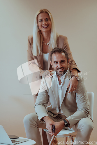 Image of A business couple posing for a photograph together against a beige backdrop, capturing their professional partnership and creating a timeless image of unity and success.