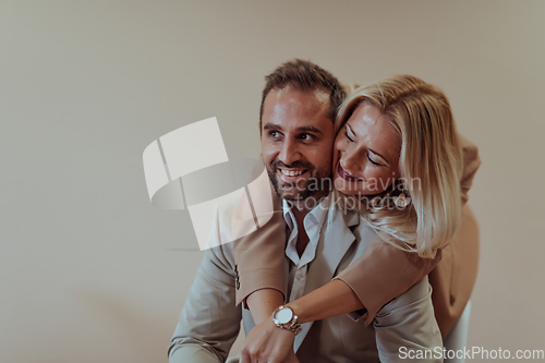 Image of A business couple posing for a photograph together against a beige backdrop, capturing their professional partnership and creating a timeless image of unity and success.