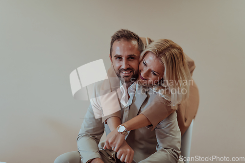 Image of A business couple posing for a photograph together against a beige backdrop, capturing their professional partnership and creating a timeless image of unity and success.