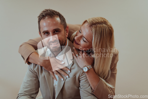 Image of A business couple posing for a photograph together against a beige backdrop, capturing their professional partnership and creating a timeless image of unity and success.