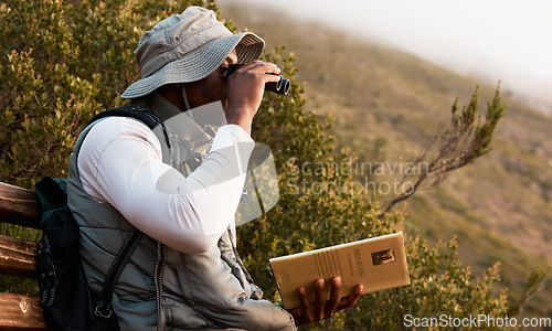 Image of Book, binocular or man bird watching in nature on trekking adventure journey for wellness or peace. Hiking, holiday vacation or African person on bench to relax or looking to search in park for view