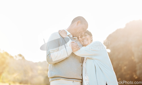 Image of Nature, sunset and senior couple hugging, laughing and bonding on a romantic date in a park. Happy, smile and elderly woman and man in retirement embracing with love, care and happiness in a field.