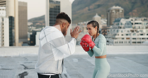 Image of Fitness, personal trainer and boxing training on rooftop in city for exercise, sport or outdoor workout. Woman boxer and man coaching in sports practice for fighting, cardio or self defense in town