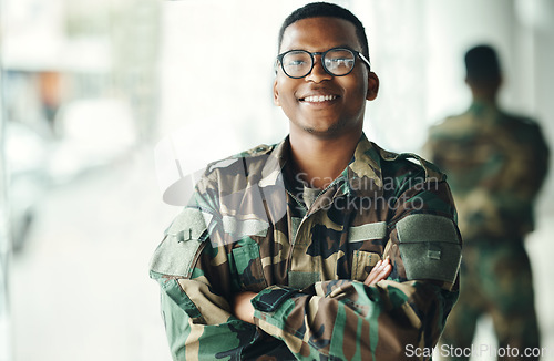 Image of Confident soldier portrait, smile and arms crossed in army building, pride and professional hero service. Military career, security and courage, black man in camouflage uniform at government agency.