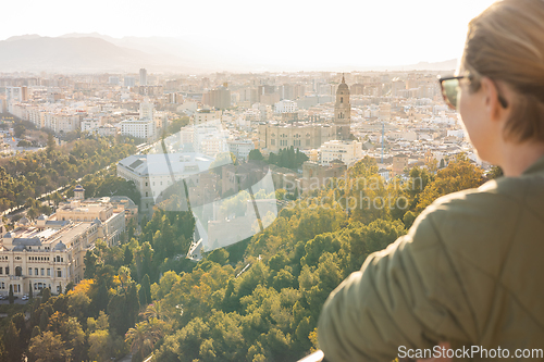 Image of Bolnde female touris enjoying amazing panoramic aerial view of Malaga city historic center, Coste del Sol, Andalucia, Spain.