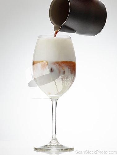 Image of coffee espresso pouring into glass of iced milk