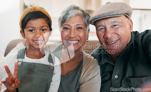 Image of Peace sign selfie, smile and a girl with her grandparents on a sofa in the living room of their home closeup. Grandmother, grandfather and granddaughter together for a photograph during a visit