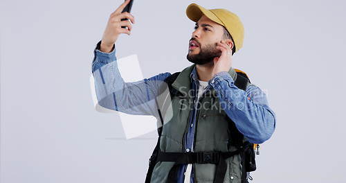 Image of Phone, service or signal with a hiking man in studio on a gray background searching for reception. Mobile, remote or lost with a young backpacker looking for connection while trekking for adventure