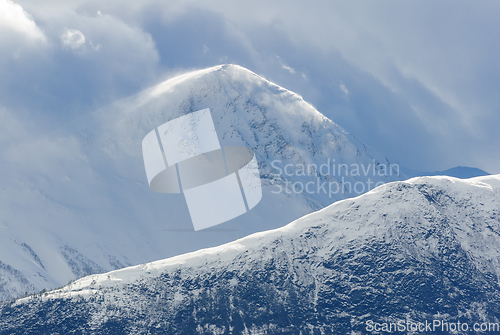 Image of snowy mountain peak between clouds