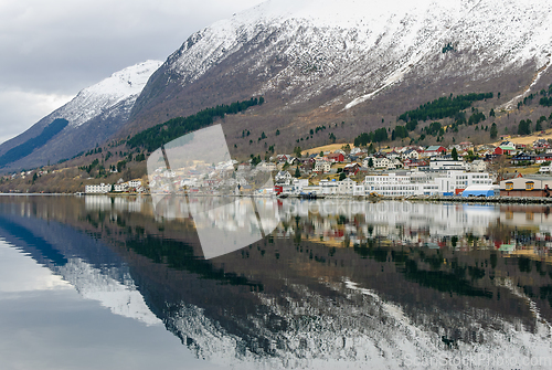 Image of small town under mountains that are reflected in the sea