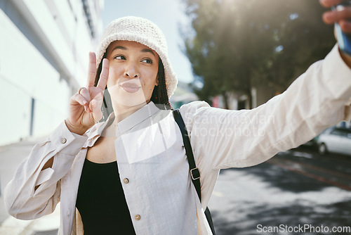 Image of Woman on city street with selfie, peace sign and travel holiday memory or social media in streetwear. Influencer, streamer or gen z girl with urban fashion, photography and content creation for blog.