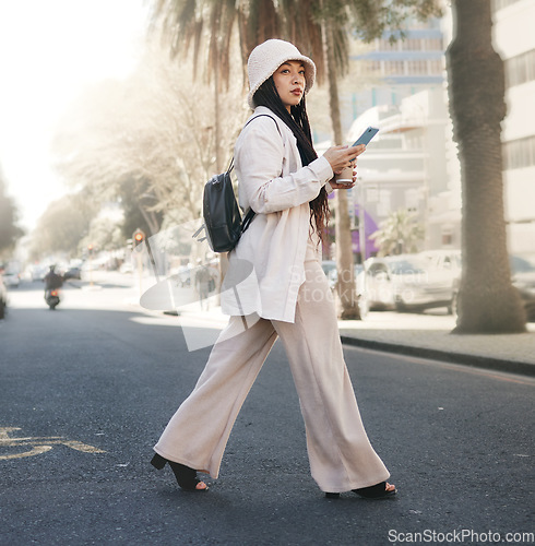 Image of Woman crossing street with phone, walking in city and travel with location app, social media and streetwear. Influencer, streamer or gen z girl with urban fashion, smartphone and direction in road.