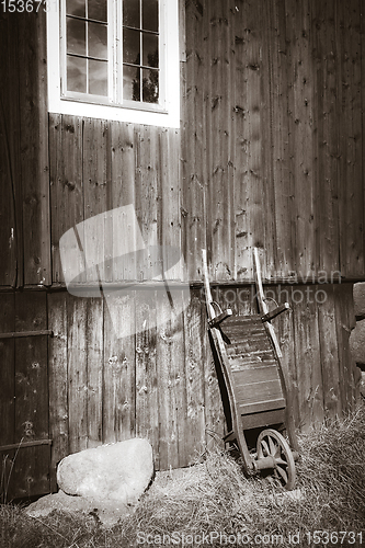 Image of Old wooden wheelbarrow on a farm wall. Black and White photograp