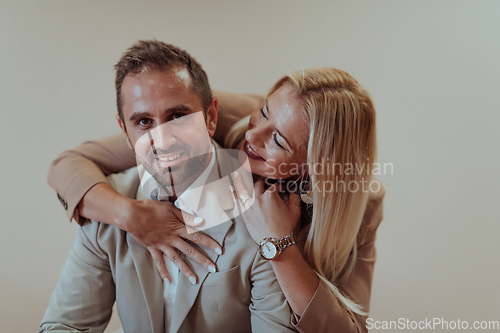 Image of A business couple posing for a photograph together against a beige backdrop, capturing their professional partnership and creating a timeless image of unity and success.