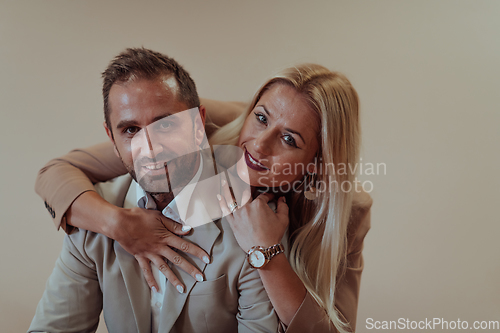 Image of A business couple posing for a photograph together against a beige backdrop, capturing their professional partnership and creating a timeless image of unity and success.