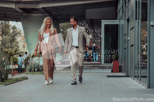 Image of Modern business couple after a long day's work, walking together towards the comfort of their home, embodying the perfect blend of professional success and personal contentment.