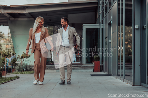 Image of Modern business couple after a long day's work, walking together towards the comfort of their home, embodying the perfect blend of professional success and personal contentment.