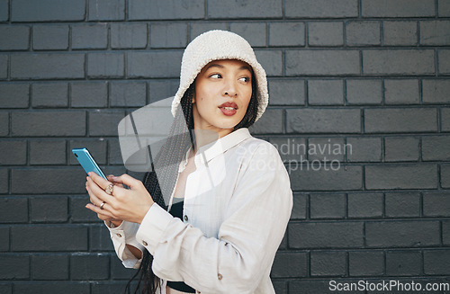 Image of Woman with phone, brick wall and urban fashion, typing social media post, chat or internet search. Streetwear, gen z girl or online influencer with smartphone for content creation and communication.