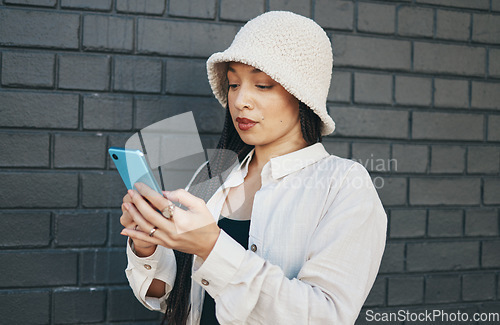 Image of Girl with phone, brick wall and urban fashion, typing social media post, chat or internet search. Streetwear, gen z woman or online influencer with smartphone for content creation and communication.
