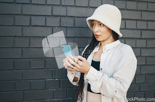 Image of Woman with phone, wall background and streetwear, typing social media post, chat or internet search. Urban fashion, gen z girl or online influencer with smartphone for content creation and technology