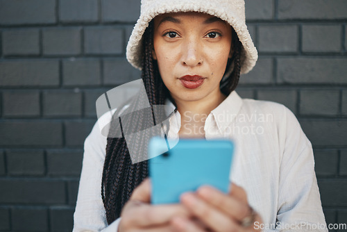 Image of Portrait of girl with phone, brick wall and urban fashion for social media, typing chat or post online. Streetwear, gen z woman or influencer on smartphone in content creation, communication and tech