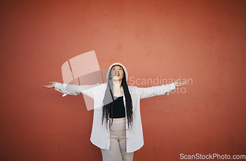 Image of Excited woman, fashion and arms up for wall and mockup space with urban style and trendy clothing. Freedom, hipster female person and confidence with red background and edgy gen z clothes of a girl