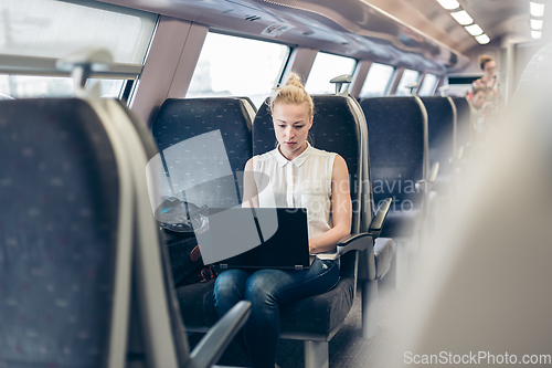 Image of Woman travelling by train working on laptop.