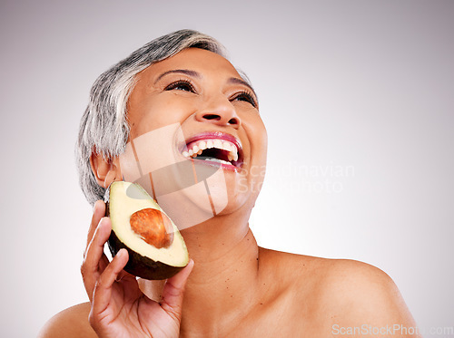 Image of Happy senior woman, avocado and studio with thinking, results and transformation for skin by white background. Mature female model, fruit and nutrition in diet, beauty and excited for transformation