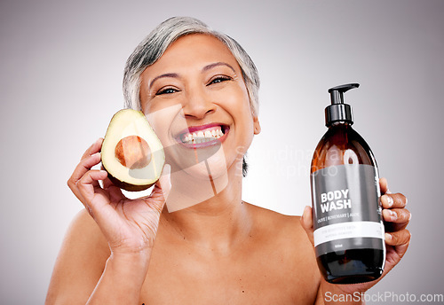 Image of Senior woman, avocado and studio portrait for bottle, product or soap for body wash by white background. Mature female model, fruit and liquid for cleaning, beauty and skincare with organic cosmetics