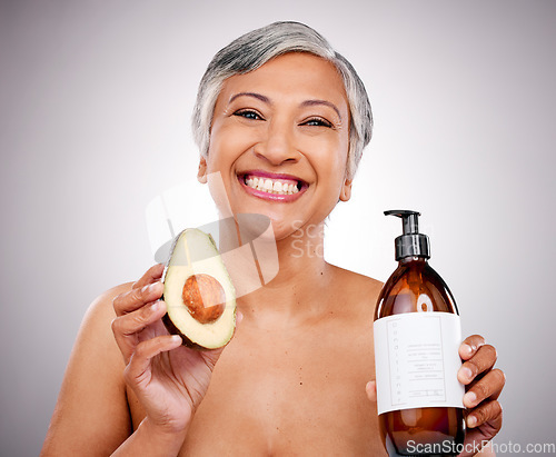 Image of Mature woman, avocado and studio portrait for bottle, product and promo for nutrition by white background. Senior female model, fruit and excited for cleaning, beauty and skincare with organic oil