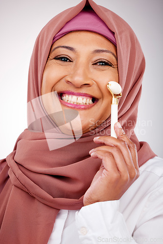 Image of Facial roller, muslim woman and skin care in studio with quartz for dermatology, cosmetics and glow. Happy mature person portrait with islam hijab, face massage and beauty on a white background