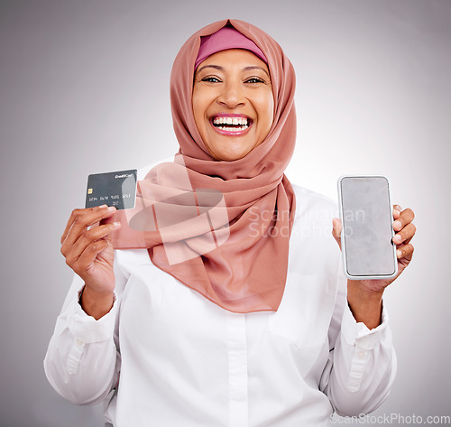 Image of Muslim woman, portrait and credit card with a phone on a studio background for online shopping. Happy, ecommerce and an Islamic person with a mobile app for banking, finance management and payment