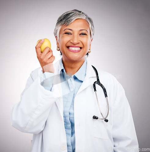 Image of Woman, doctor and portrait with apple in studio for vitamin c benefits, health and care on grey background. Happy mature dietician, nutritionist and healthy food to lose weight with fruits for detox